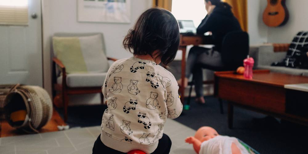 Parent feeding toddler while working from home, illustrating caregiving conflict with jury service